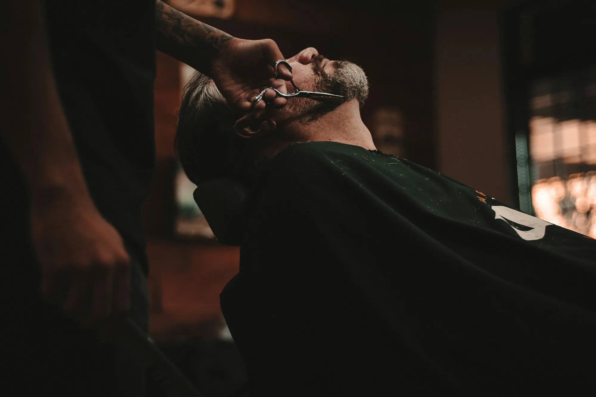 A barber at NOIR Barber Studio trimming a client's beard with precision scissors